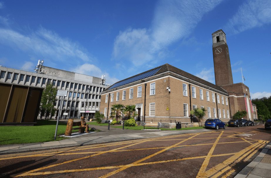 A large civic building with a clock tower under a blue sky.