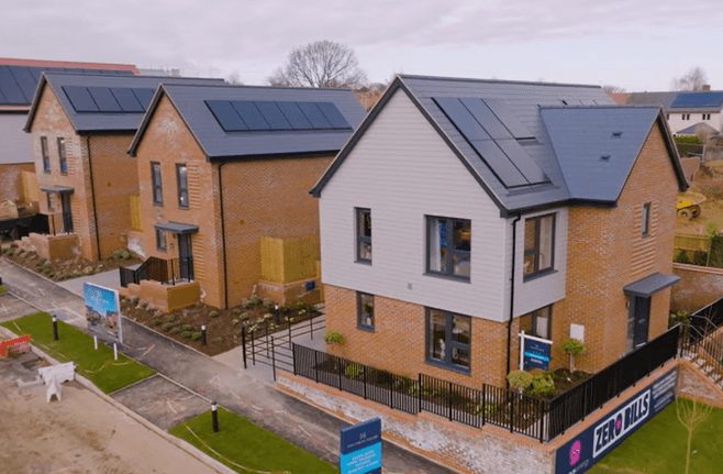 New houses with solar panels on their roofs, and an Octopus Zero Bills banner on the site fence.