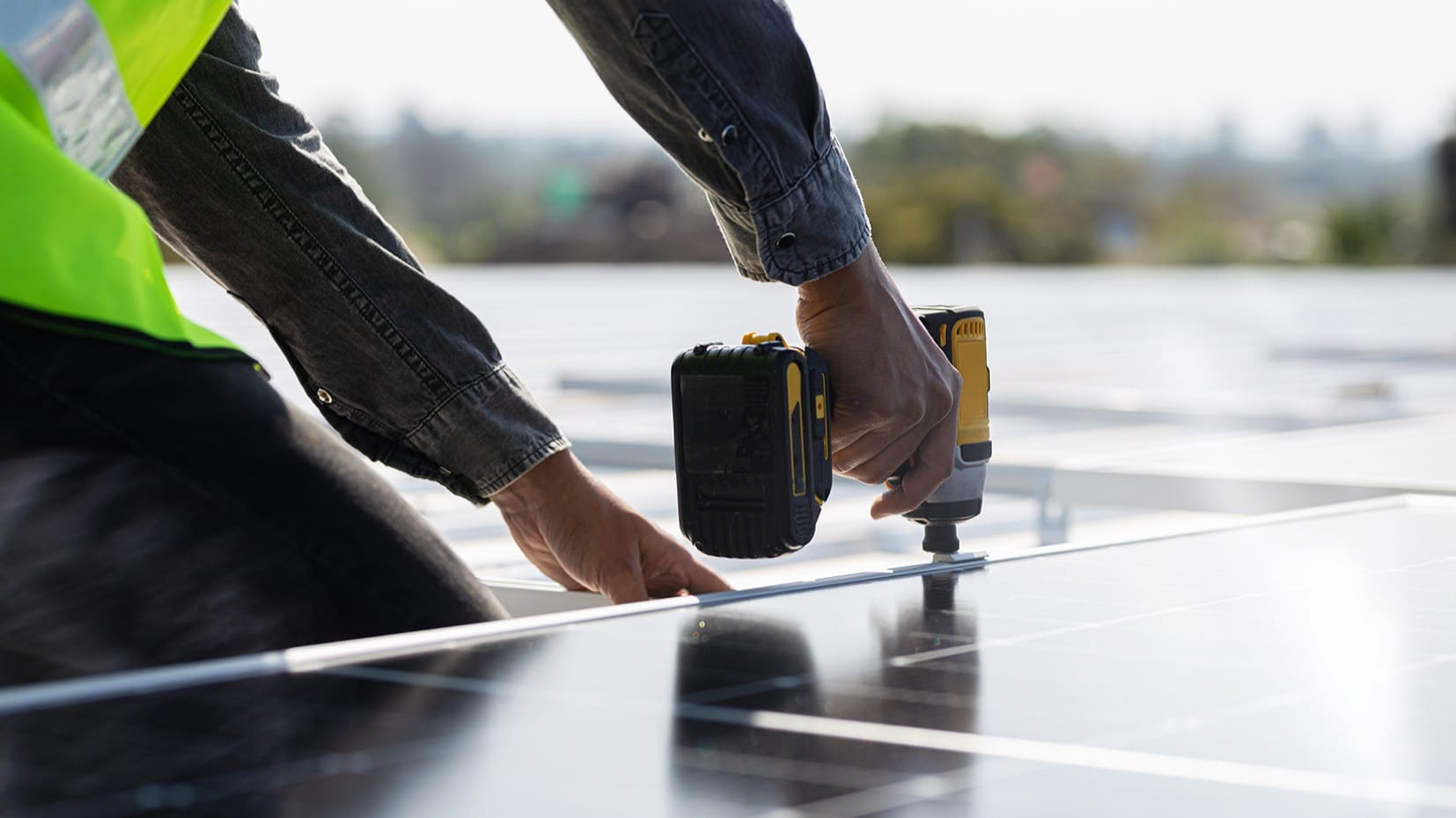 Close-up of an installer's hands fixing a solar panel into place on a roof.