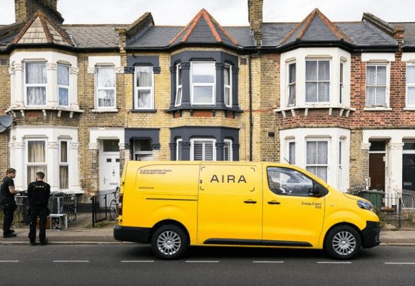 A yellow Aira van parked outside a terrace of Victorian houses.
