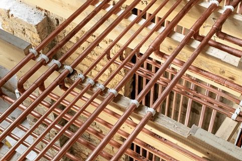 A network of copper pipes running through the ceiling void of a building.