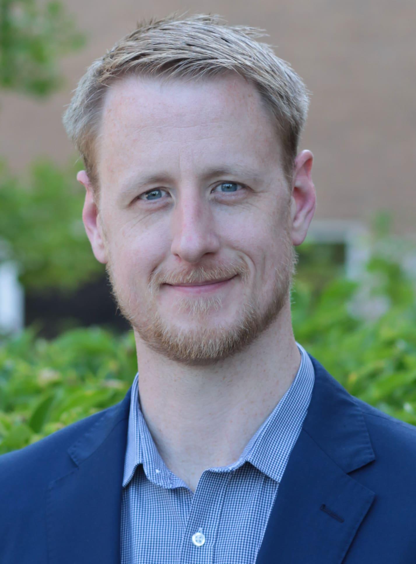 Headshot of Niall Parkin, Sustainable Fuels Product Manager, in a navy jacket, outdoors.
