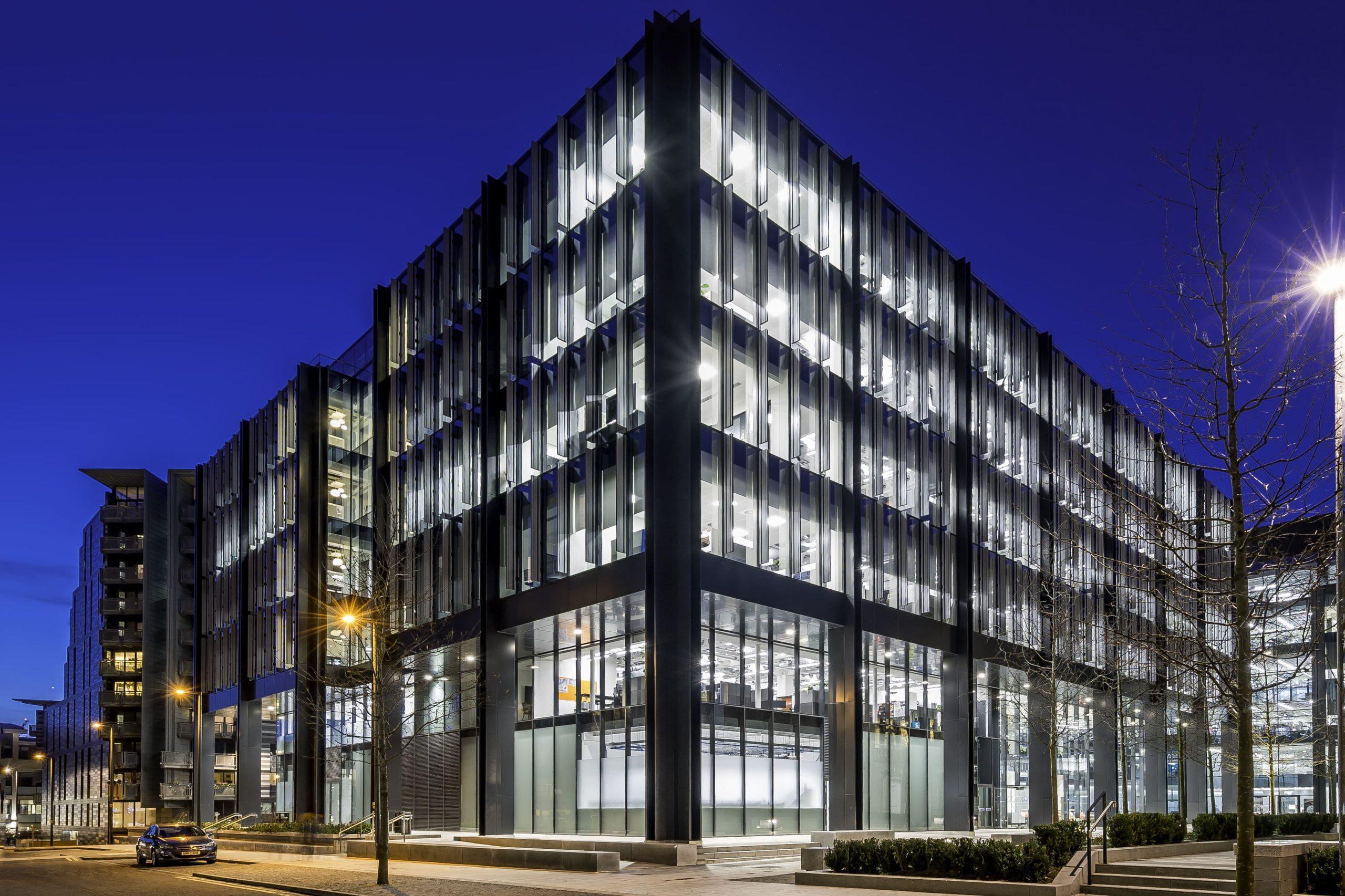The glass-fronted Cirrus Logic office building in Edinburgh, lit up at dusk.