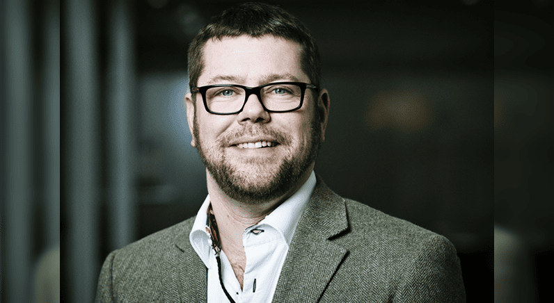Graeme Stewart of Check Point, smiling, in glasses and a grey jacket.